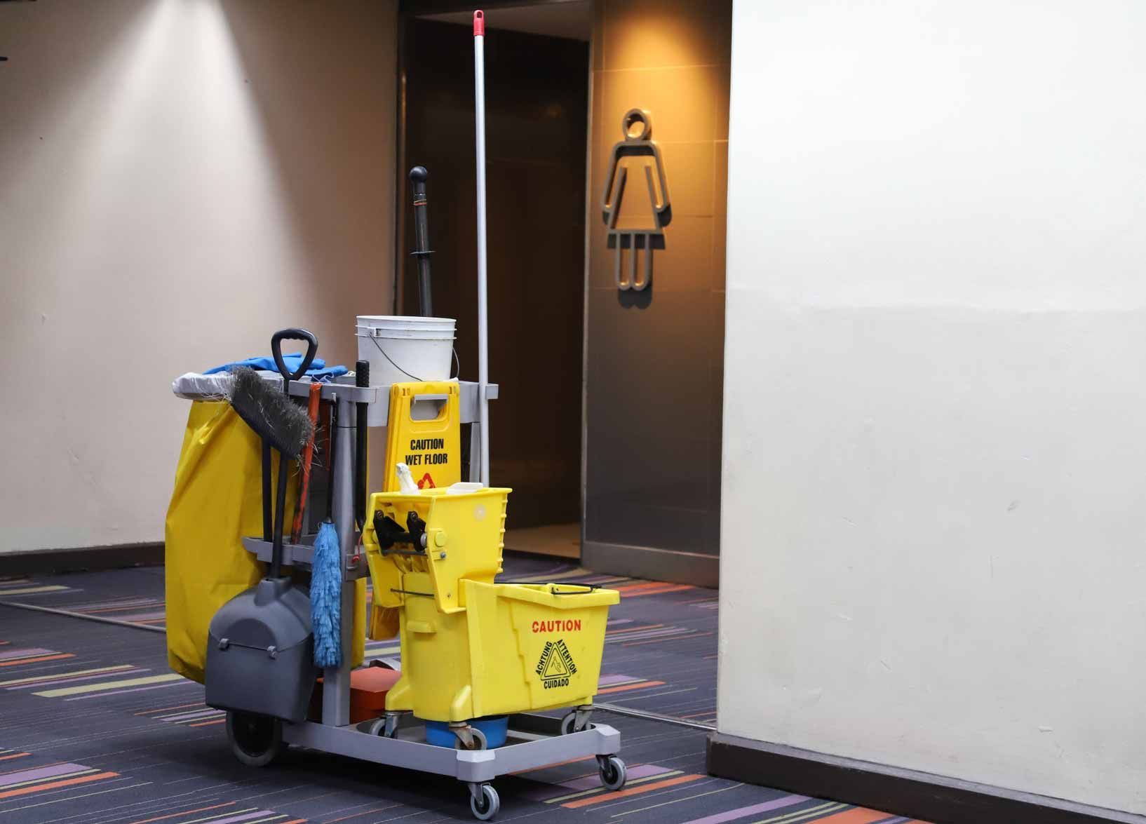 Cleaning cart with yellow bins and supplies in a hallway