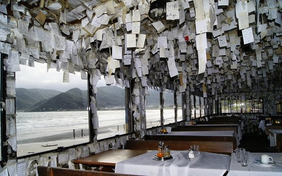 Interior do Bar do Arante em Florianópolis, com bilhetes nas paredes e vista para o mar