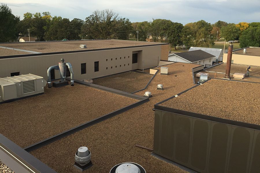 Image B of Fertile-Beltrami School in Fertile, MN, featuring a newly built-up roof and updated wall panels. Image B shows the Fertile-Beltrami School in Fertile, MN, featuring a newly built-up roof and updated wall panels.