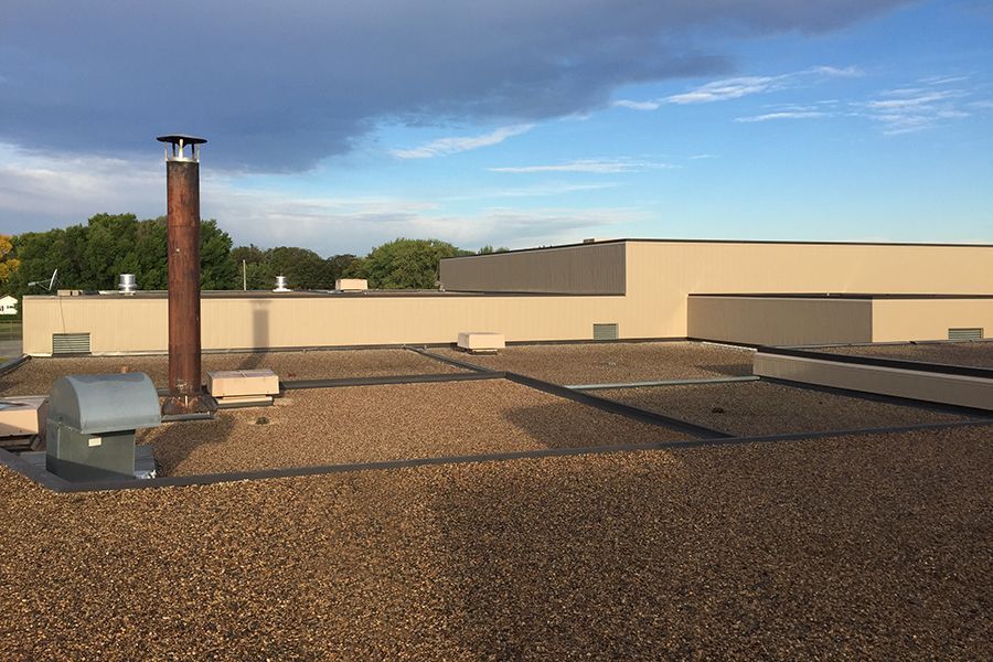 Image A of Fertile-Beltrami School in Fertile, MN, featuring a newly built-up roof and updated wall panels. Image A shows the Fertile-Beltrami School in Fertile, MN, featuring a newly built-up roof and updated wall panels.