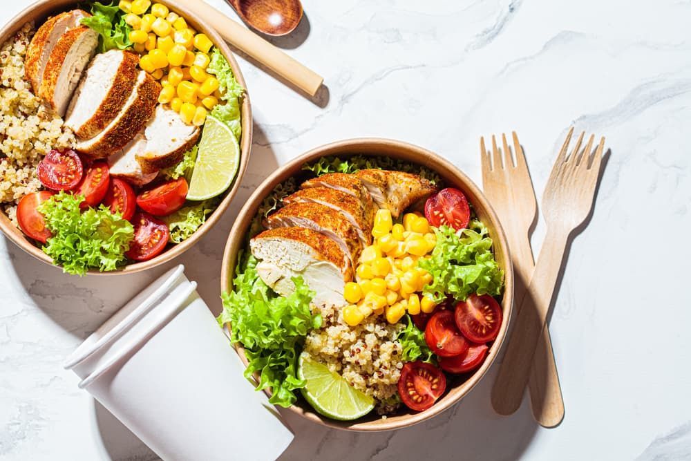 Two Bowls of Food with Chicken and Vegetables on A Table — Brews & Bites Beachside Cafe in Meikleville Hill, QLD