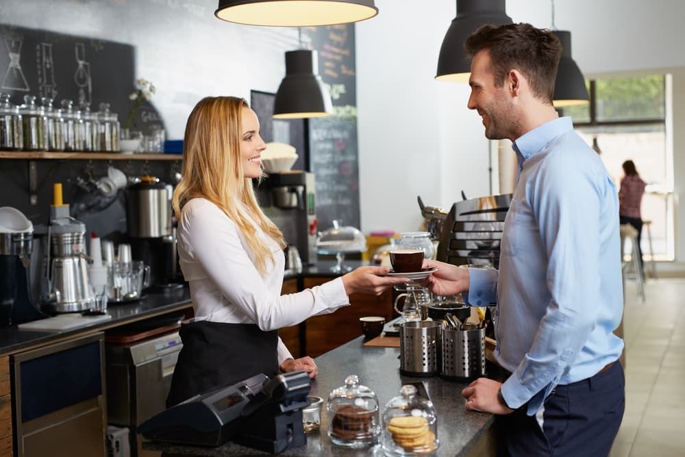 A Man Is Paying for A Cup of Coffee at A Coffee Shop — Brews & Bites Beachside Cafe in Meikleville Hill, QLD