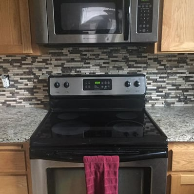 A stove with a microwave above it in a kitchen.