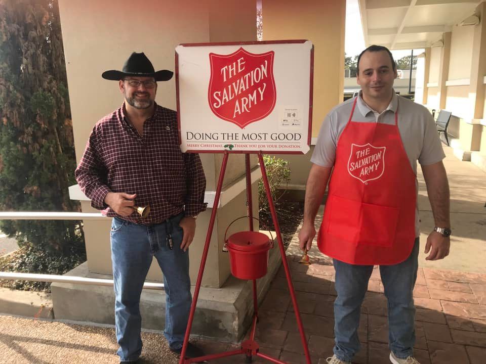 Two men are standing in front of a salvation army sign.