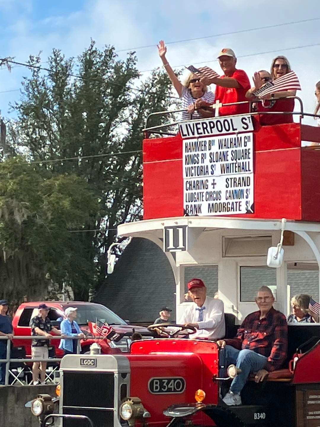 A group of people are sitting on top of a red tractor in a parade.