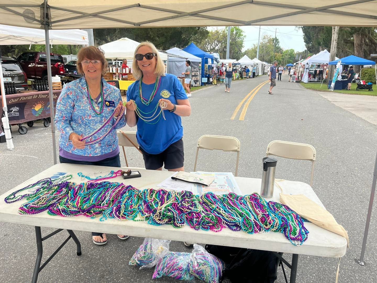 Two women are standing next to a table with beads on it.