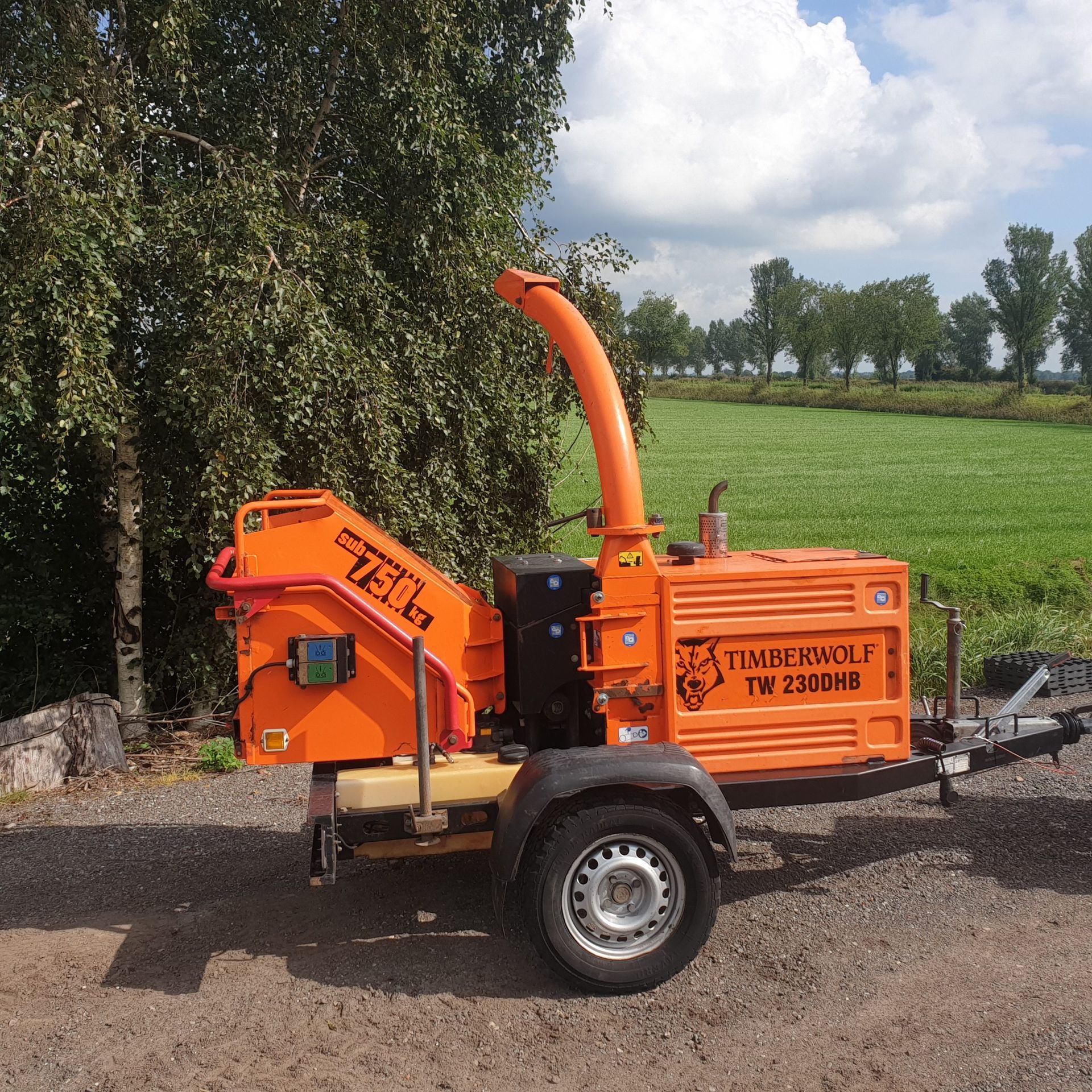 A lawnmower is parked in a gravel area with trees in the background