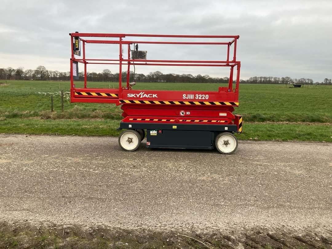 A red scissor lift is parked on the side of a road.