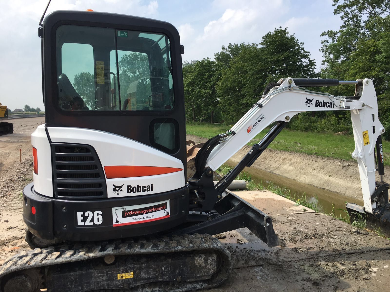 A bobcat e26 mini excavator is parked on a dirt road.