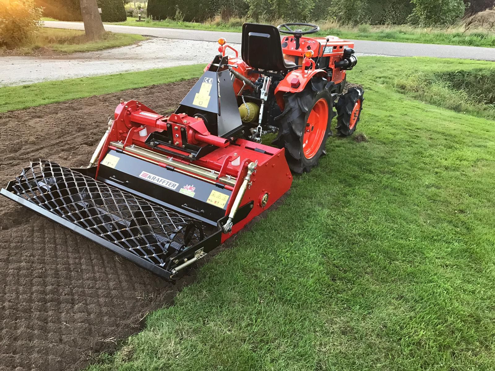 A small tractor is sitting on top of a lush green lawn.
