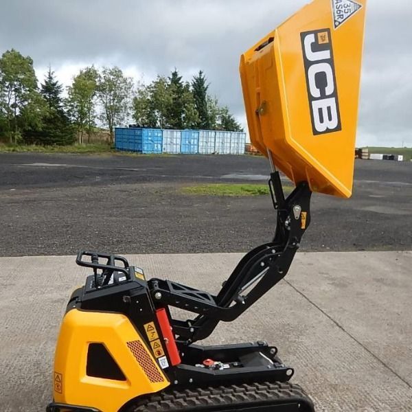 A yellow jcb dump truck is parked on the side of the road