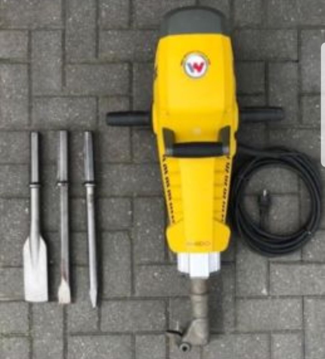 A yellow machine with a w on it is sitting on a brick floor