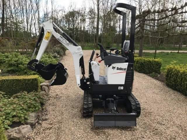 A small excavator is parked on a gravel road.