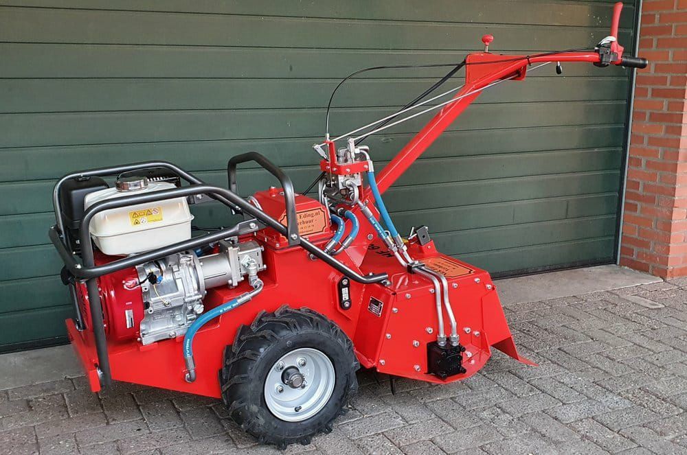 A red tractor is parked in front of a garage door