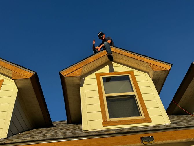 Person on roof of yellow house under clear blue sky