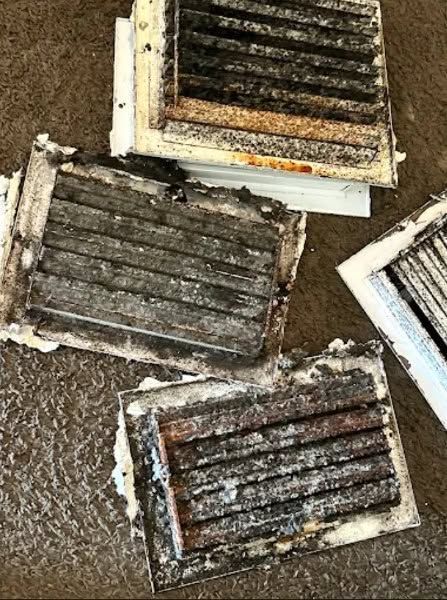 Dirty, rust-streaked metal grates arranged on a wet concrete surface