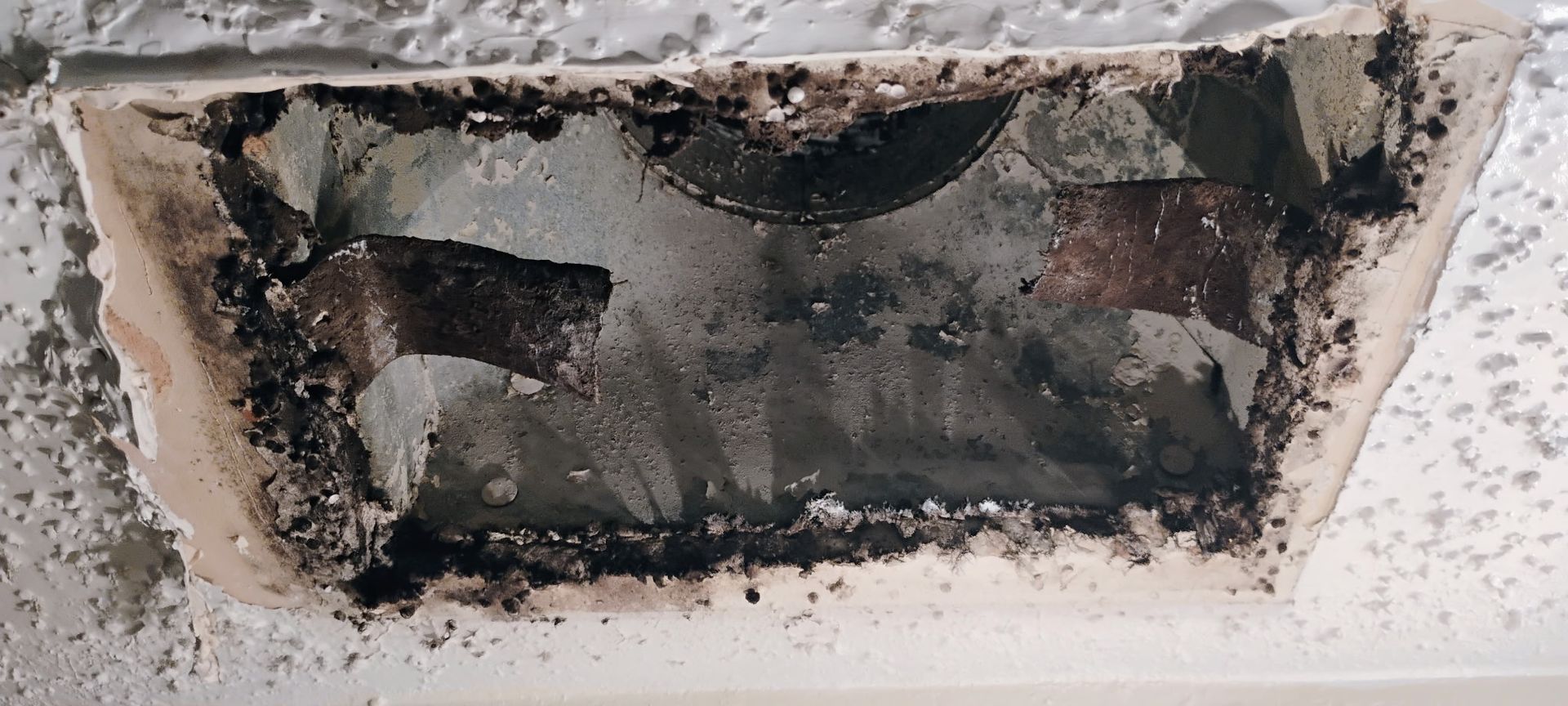 Damaged recessed wall opening with black soot and crumbling plaster around the edges