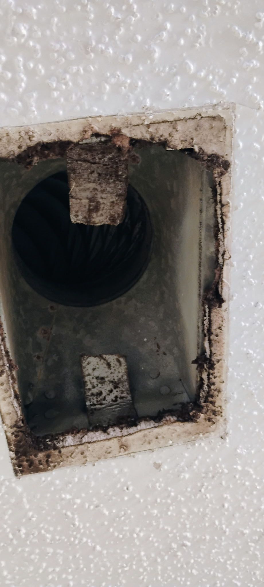 Ceiling vent opening with exposed duct and insulation around the frame.