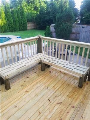 A wooden bench is sitting on a wooden deck next to a pool.