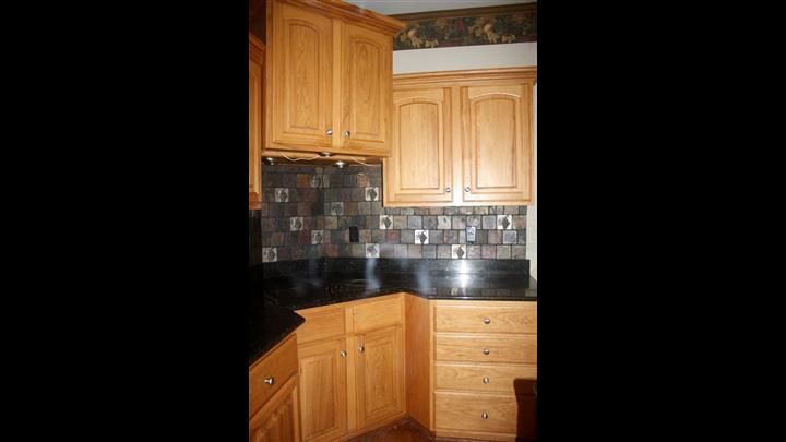 A kitchen with wooden cabinets and black counter tops