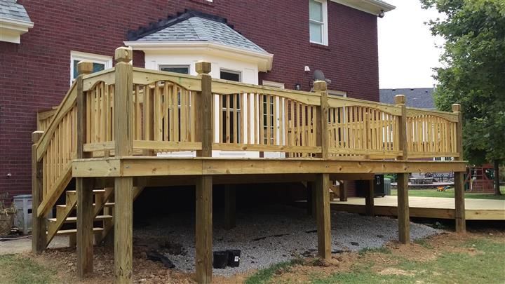 A large wooden deck is sitting in front of a brick house.