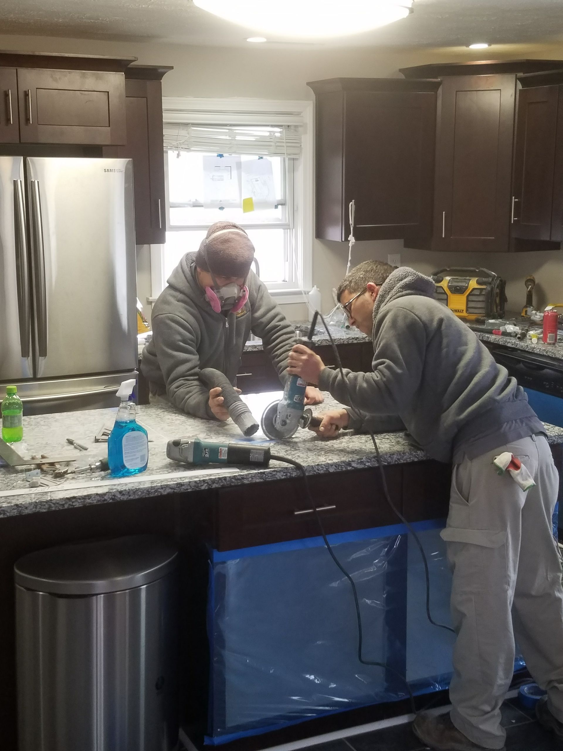 Two men are working on a counter in a kitchen