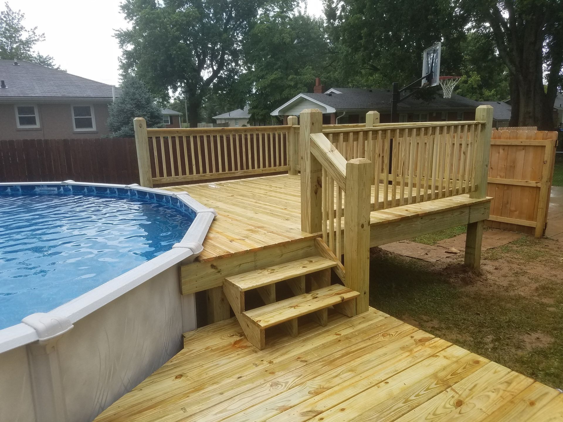 A wooden deck with stairs leading to a pool.