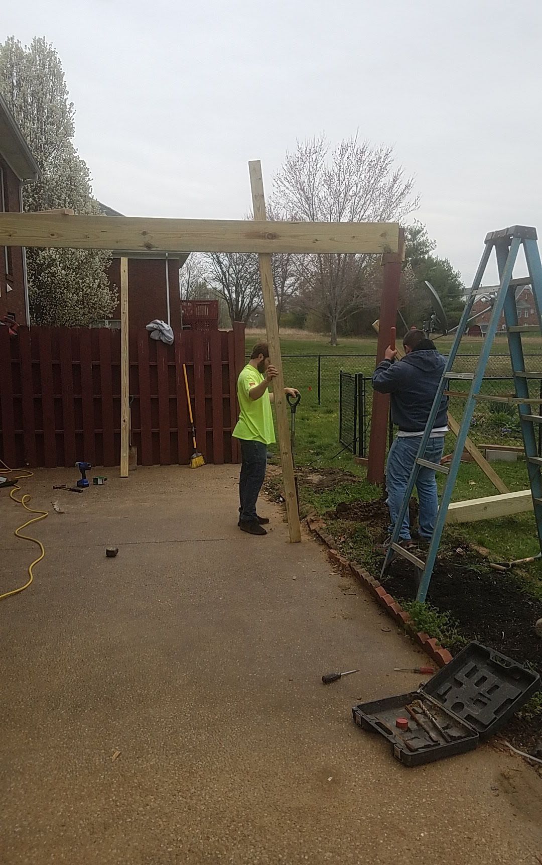 A group of men are working on a wooden structure in a driveway.