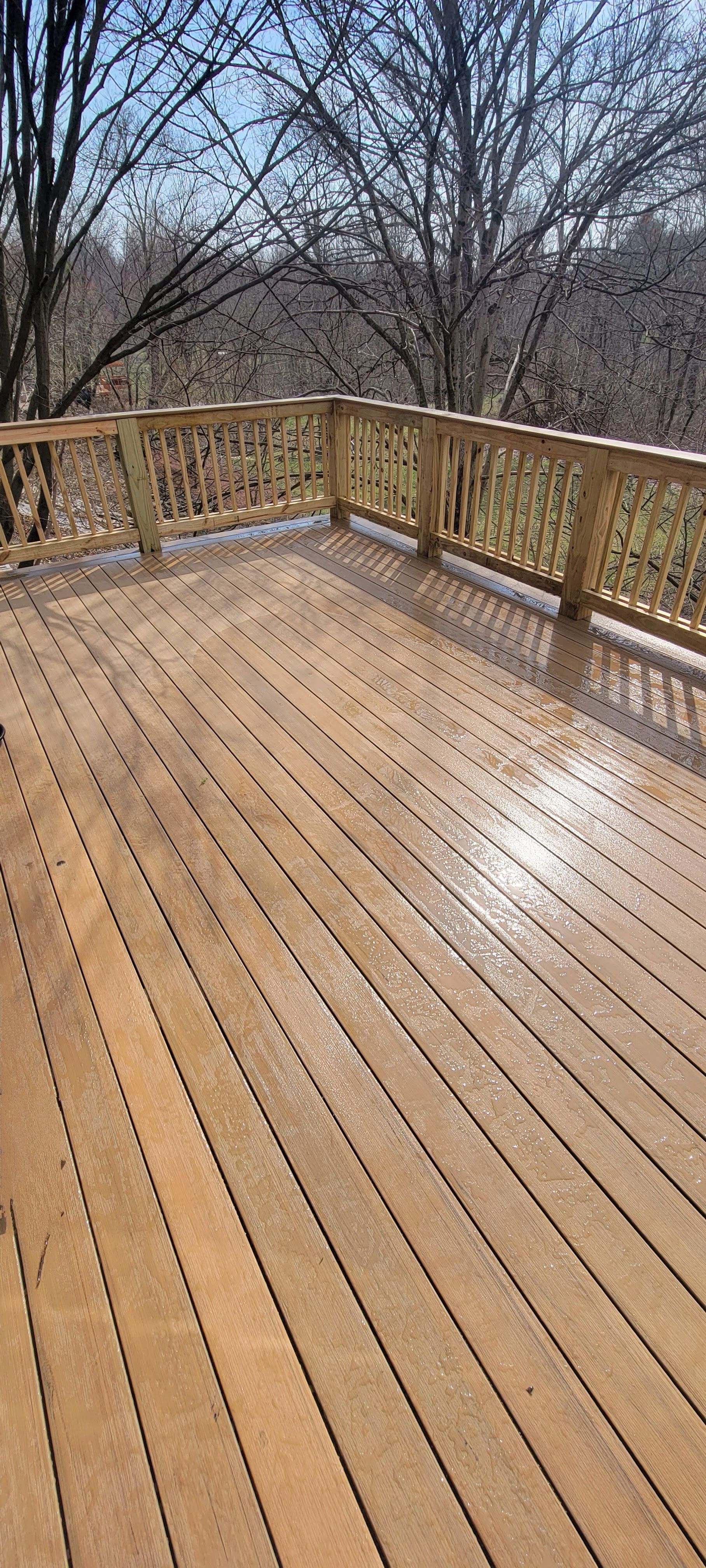 A wooden deck with a wooden railing and trees in the background.