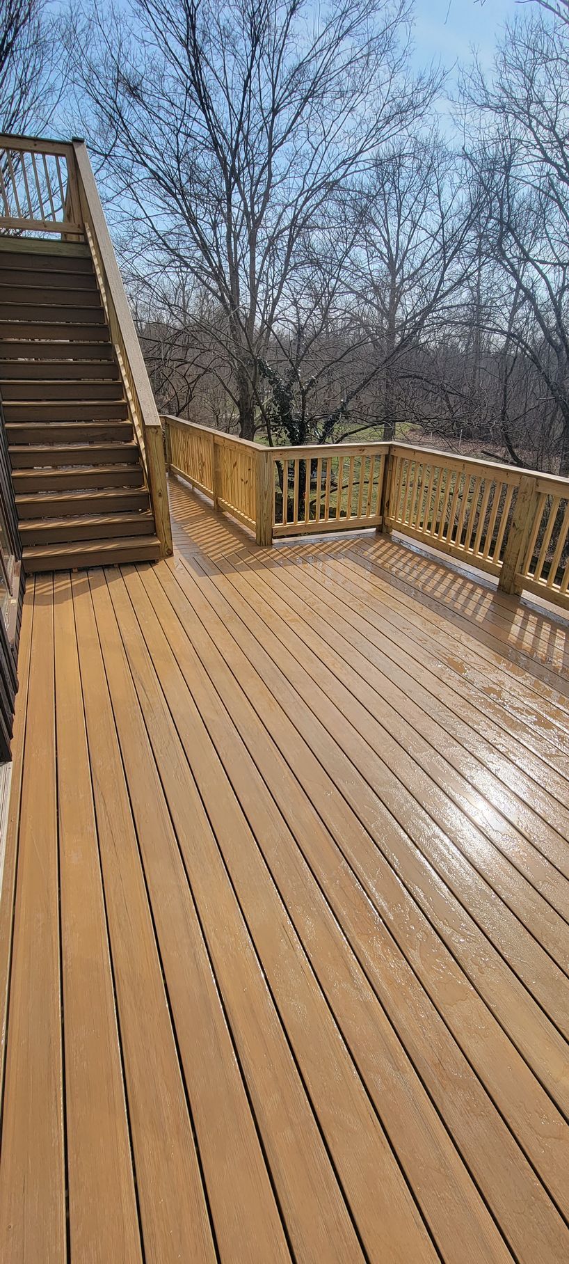 A wooden deck with stairs leading up to it and trees in the background.