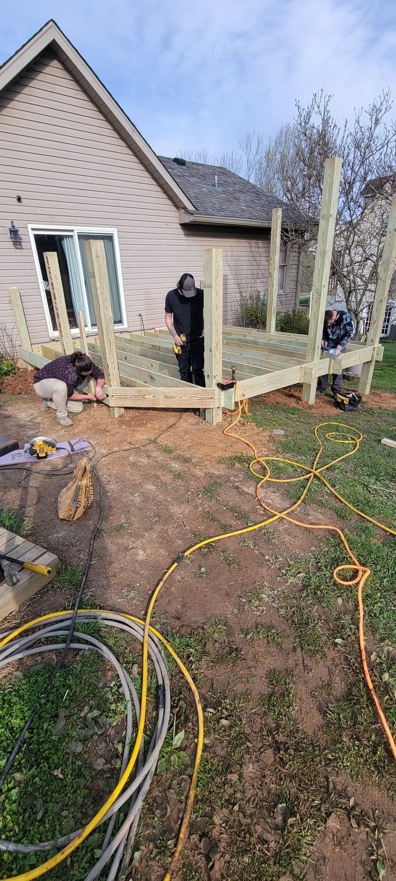 A man is standing on a wooden deck in front of a house.