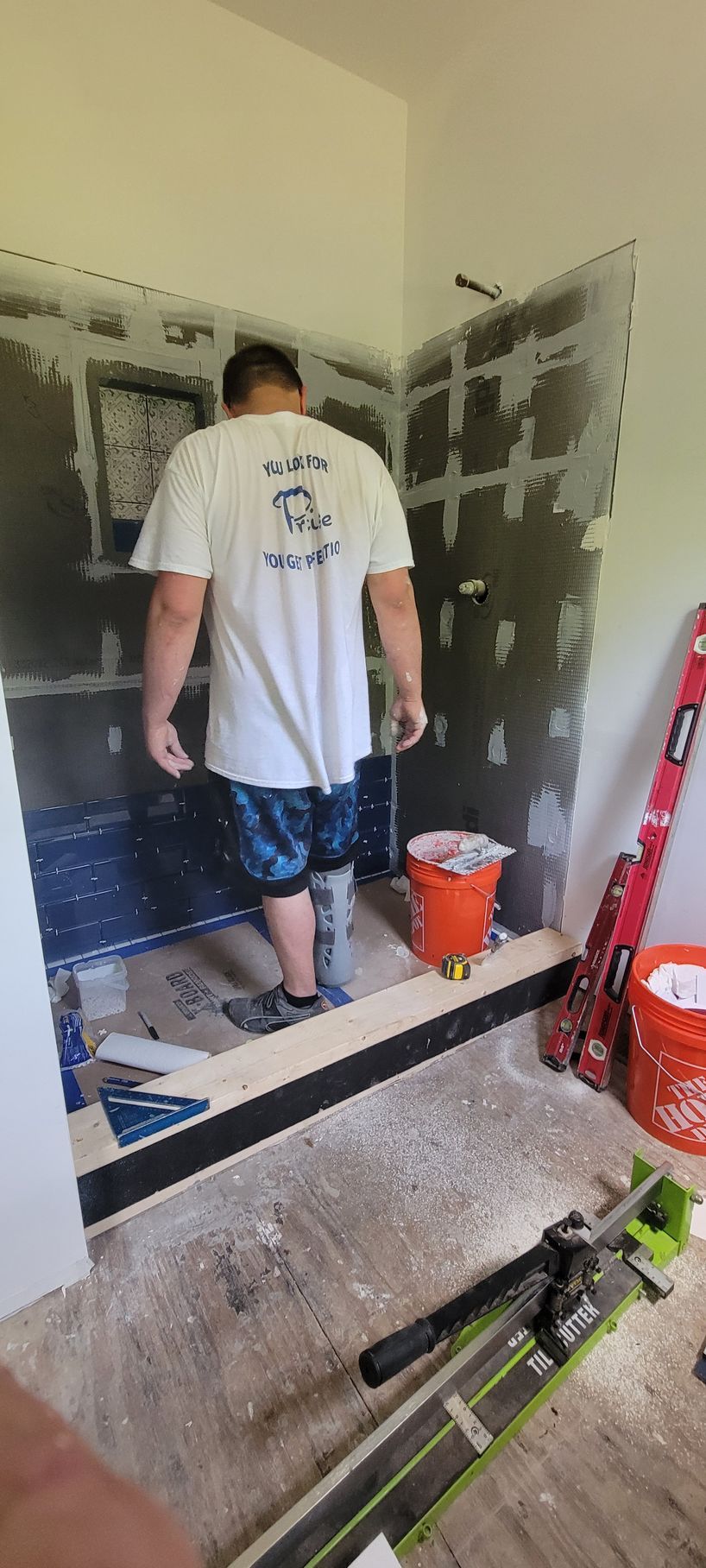 A man is standing in a bathroom under construction.