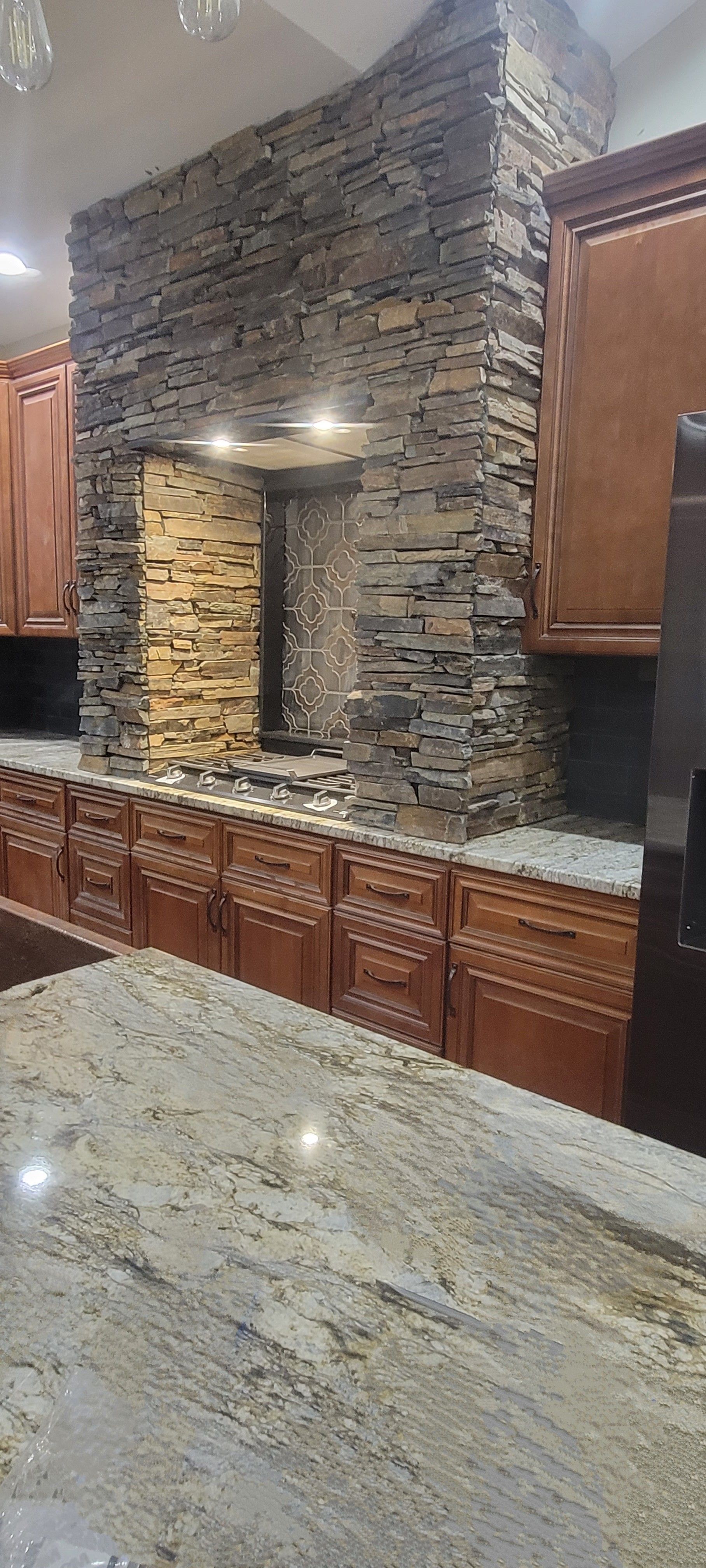 A kitchen with a stone fireplace and granite counter tops.