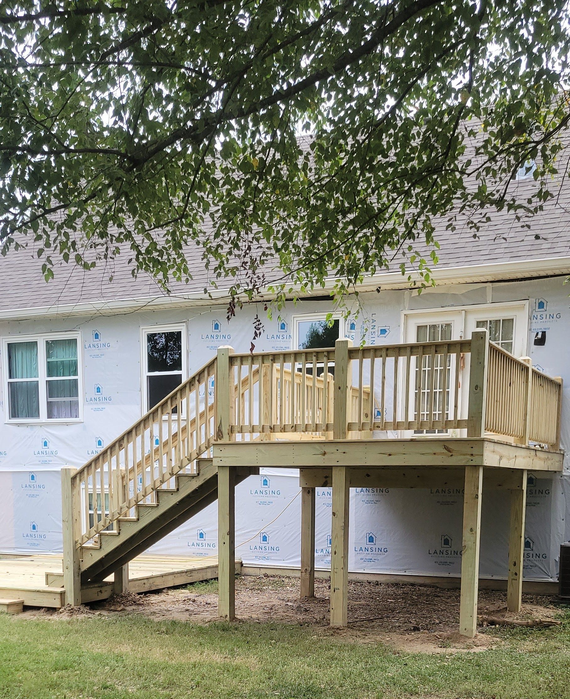 A house with a wooden deck and stairs in front of it.