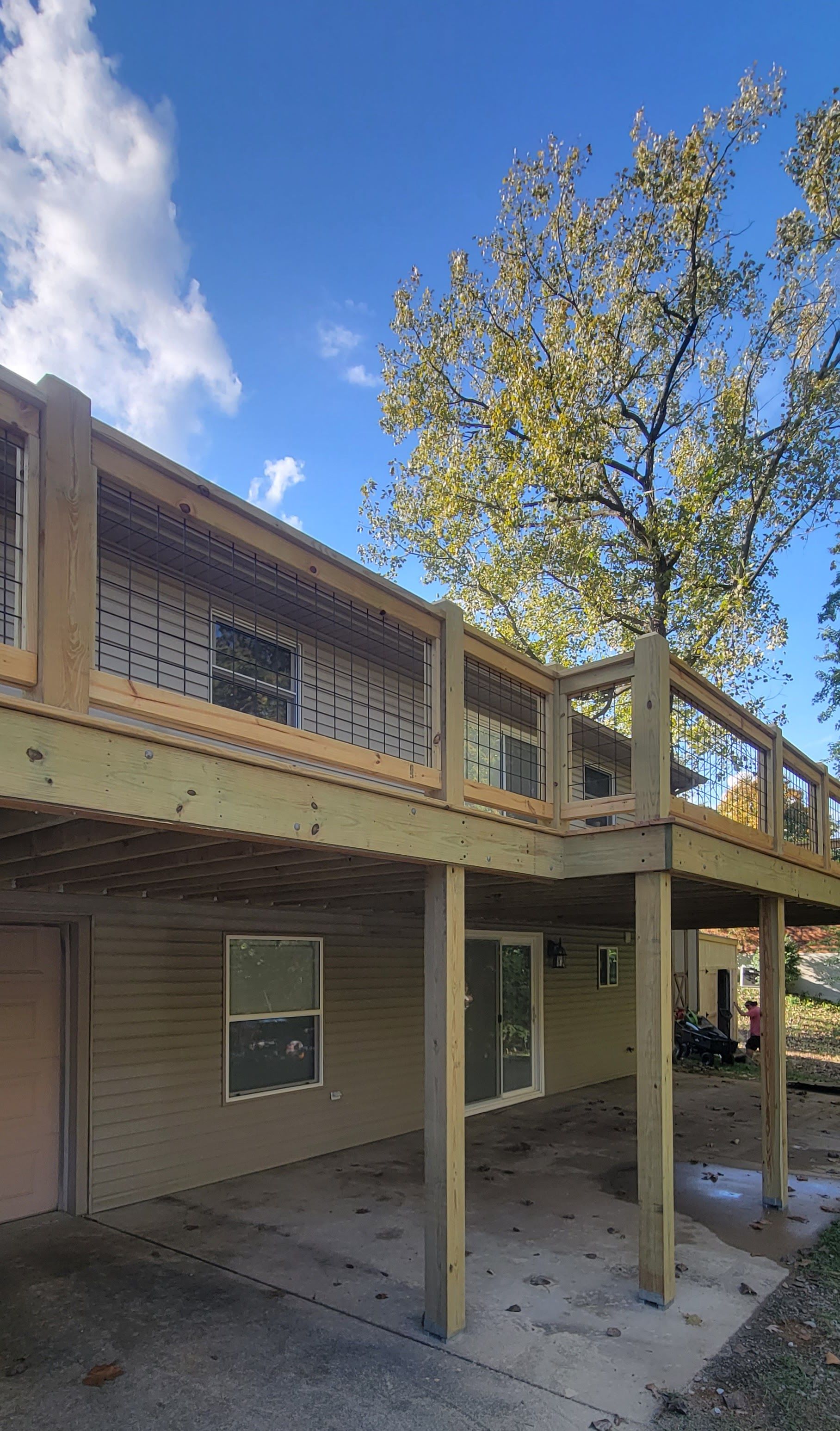 A house with a large wooden deck underneath it.