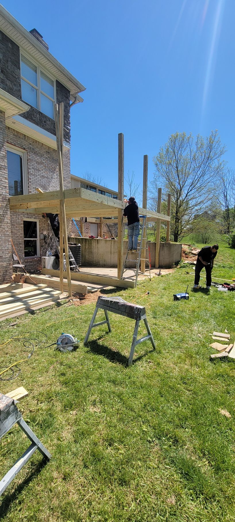 A man is building a deck in the backyard of a house.