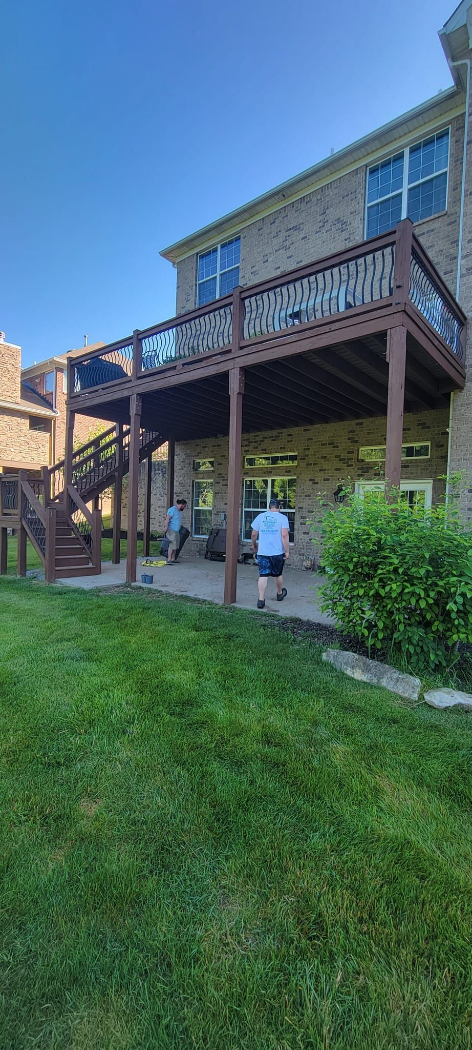 A large wooden deck with stairs is in the backyard of a house.