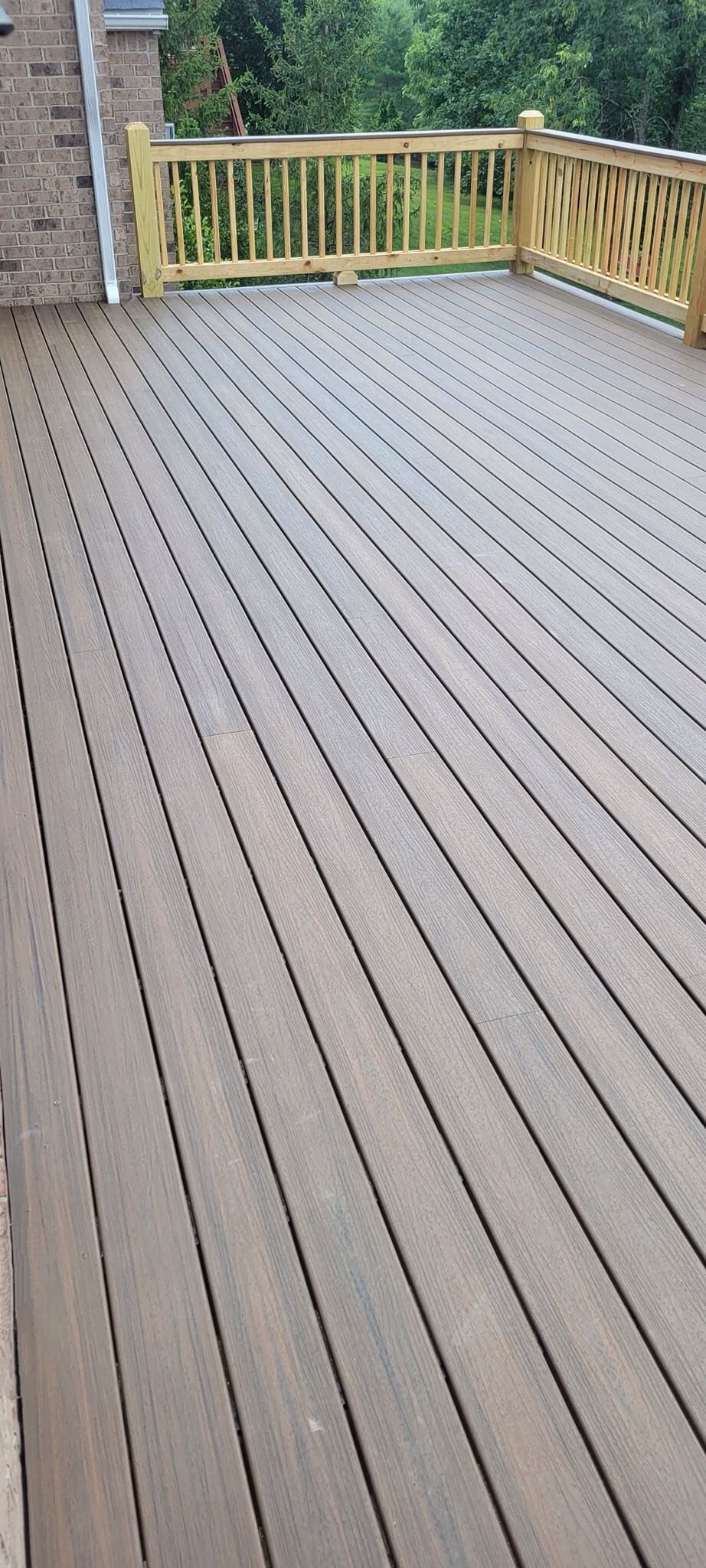 A wooden deck with a wooden railing and trees in the background.
