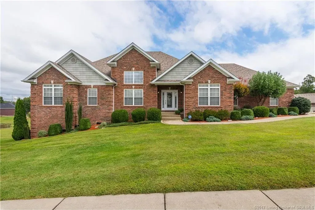A large brick house with a lush green lawn in front of it.