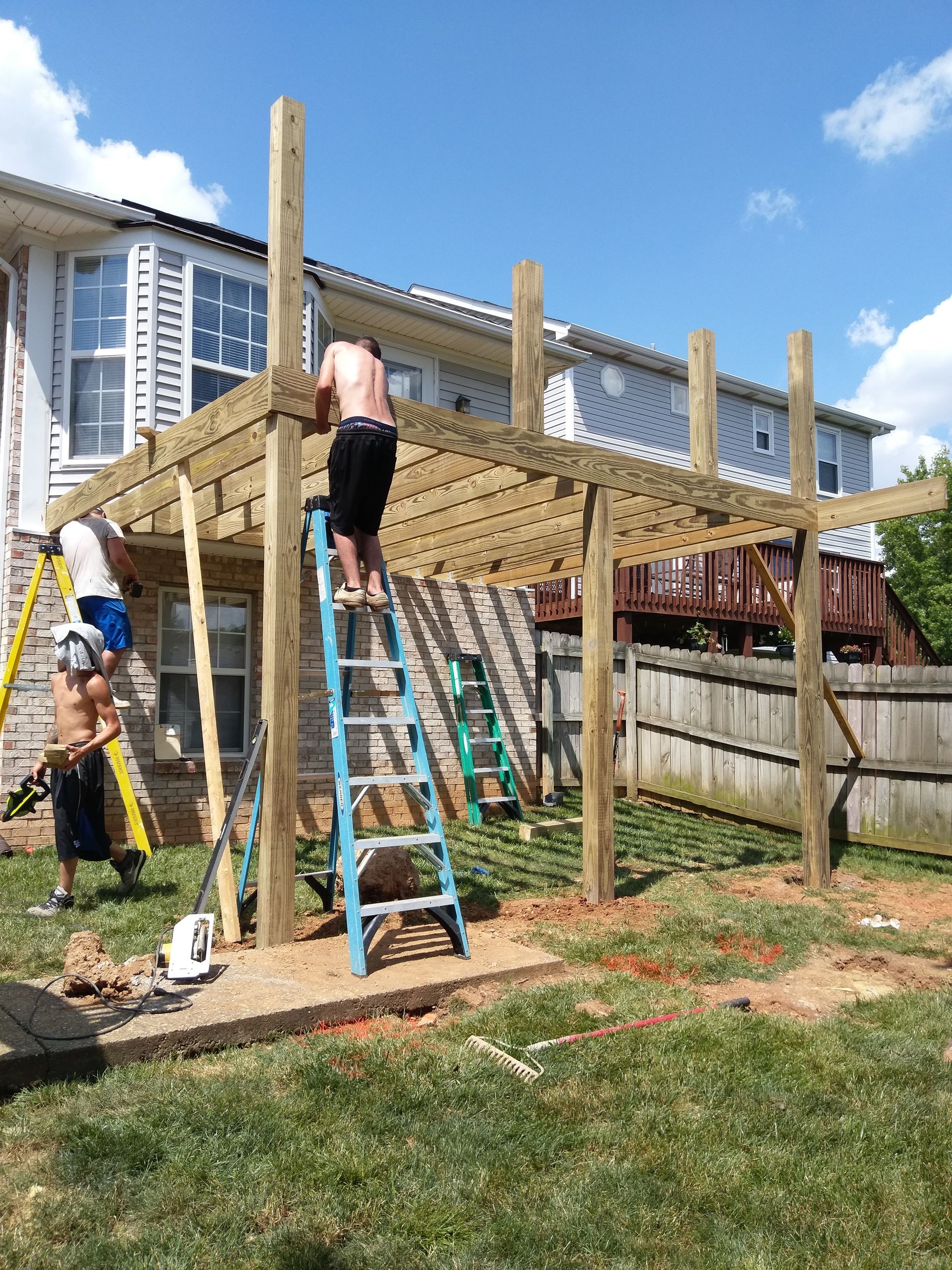 A group of men are working on a wooden deck in front of a house.