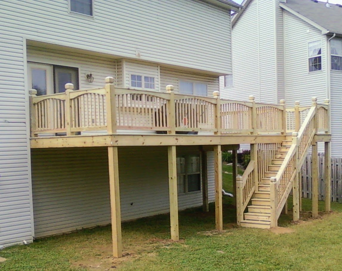 A wooden deck with stairs leading up to it is in front of a house.