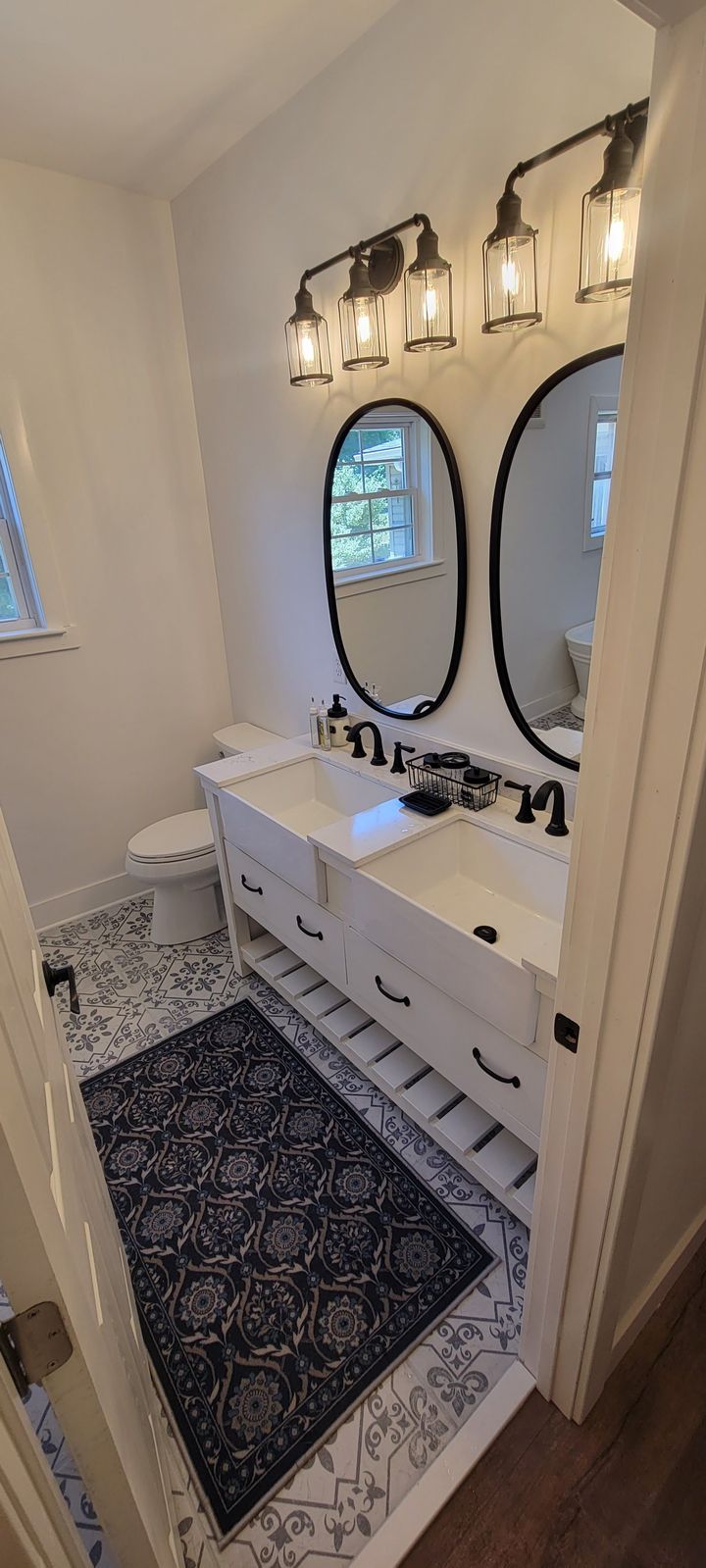 A bathroom with two sinks , two mirrors and a rug.