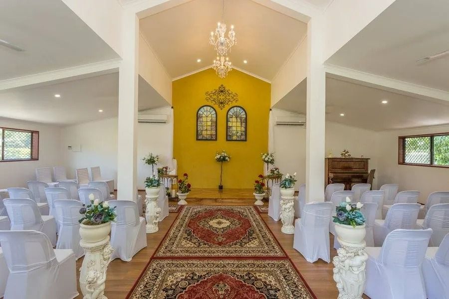 Wedding Chapel Interior With Chairs, Floral Decor, and a Red Rug Leading to a Yellow Altar — Villa Lamor in Balberra, QLD