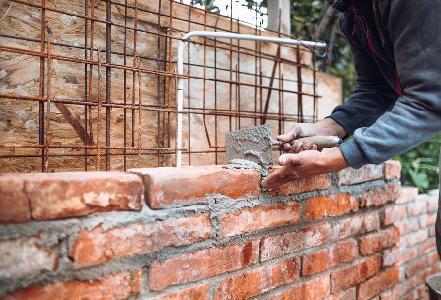 Worker laying wet mortar on a brick wall under construction