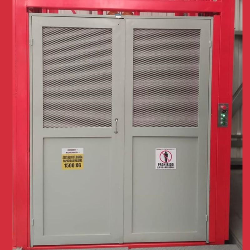 Puerta industrial doble gris con paneles de malla, encajada en un marco rojo, con señales de advertencia y un teclado
