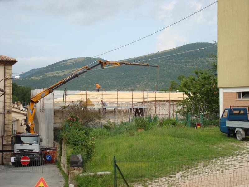 Un camion con attaccata una gru è parcheggiato davanti a un edificio in costruzione