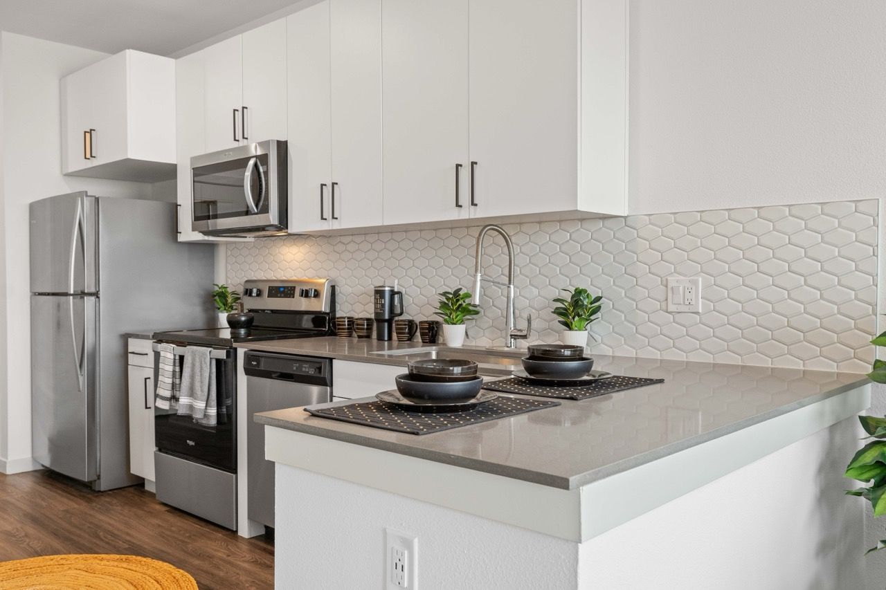 Modern kitchen with white cabinets, stainless steel appliances, and a gray island countertop.