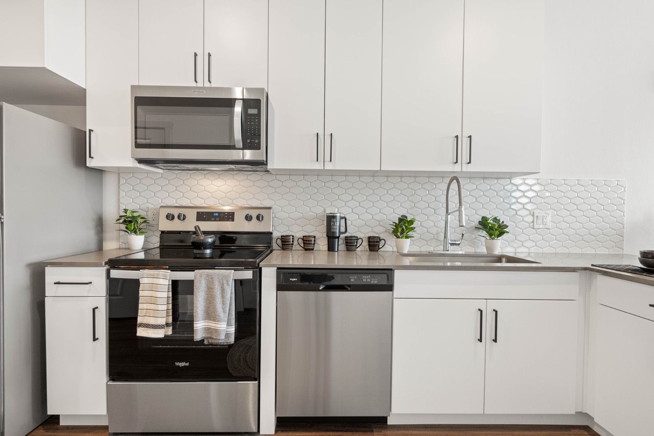 Bright modern kitchen with white cabinets, stainless steel appliances, and a tile backsplash.