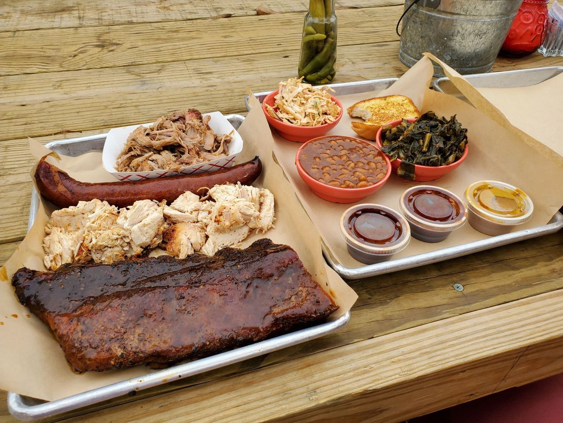 two trays of food are sitting on a wooden table .