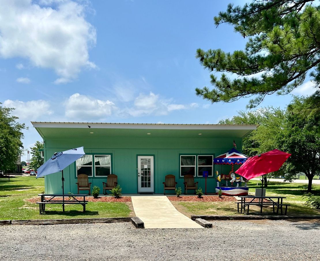 A green house with umbrellas and chairs in front of it
